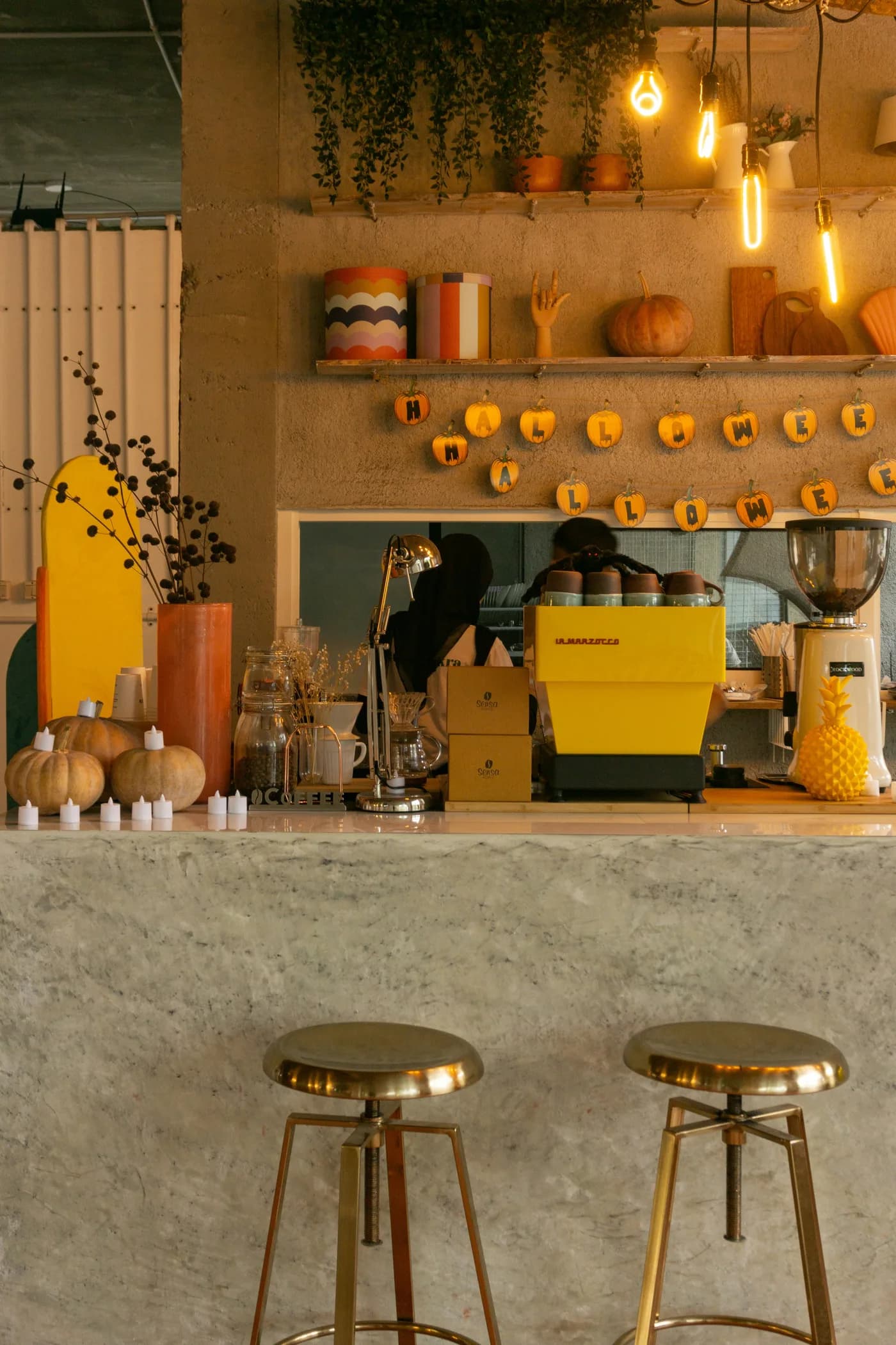 Café counter with a bright yellow La Marzocco espresso machine under warm filament bulbs